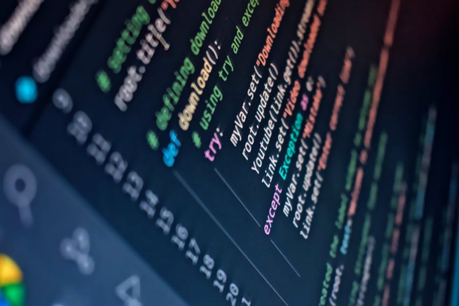 A close-up image of a person's hand typing on a silver laptop keyboard, displaying lines of color-coded code on the screen. The person's wrist is adorned with a black watch. The laptop is placed on a 